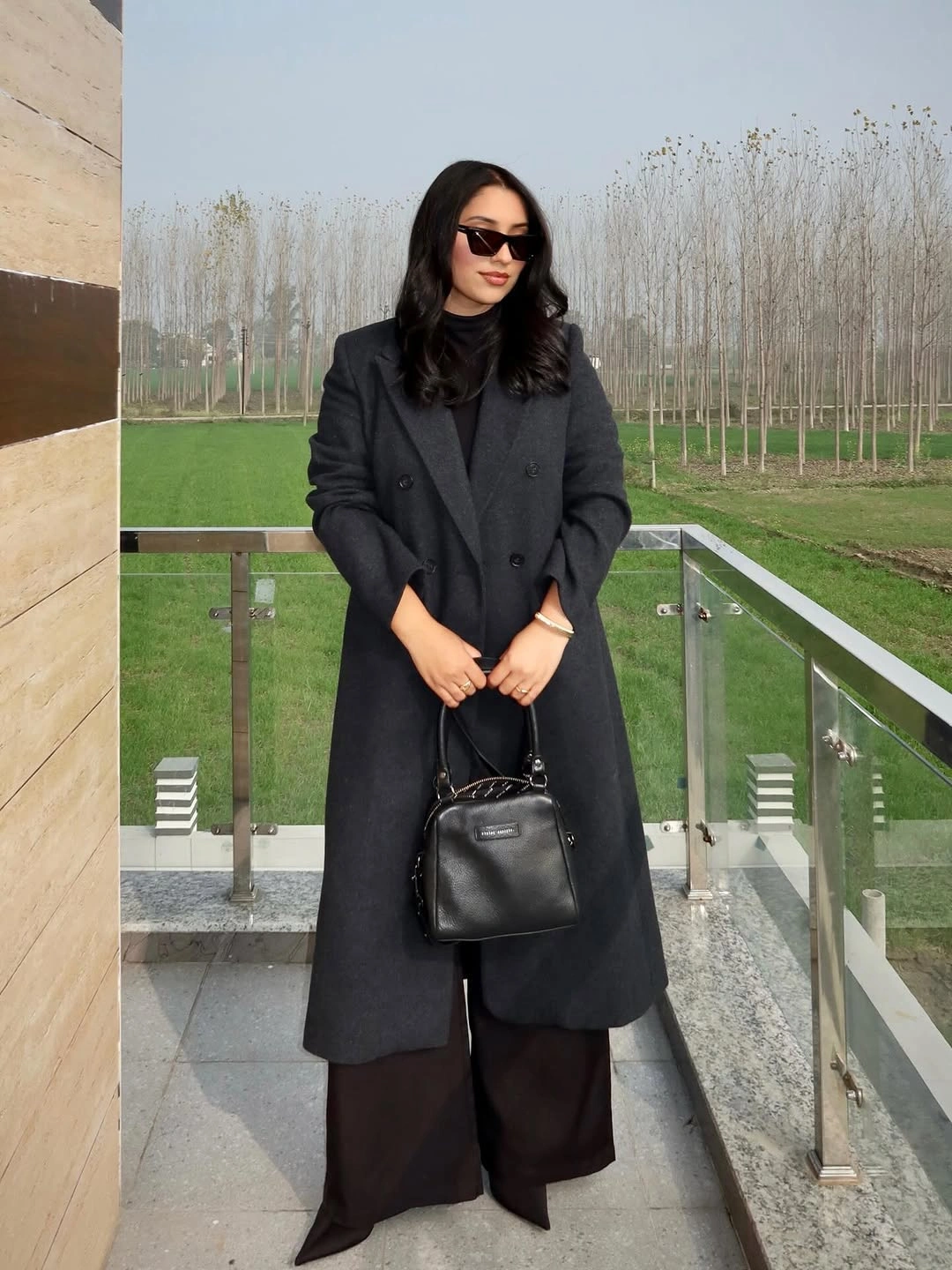 Charcoal double-breasted coat with wide dark trousers and black handbag