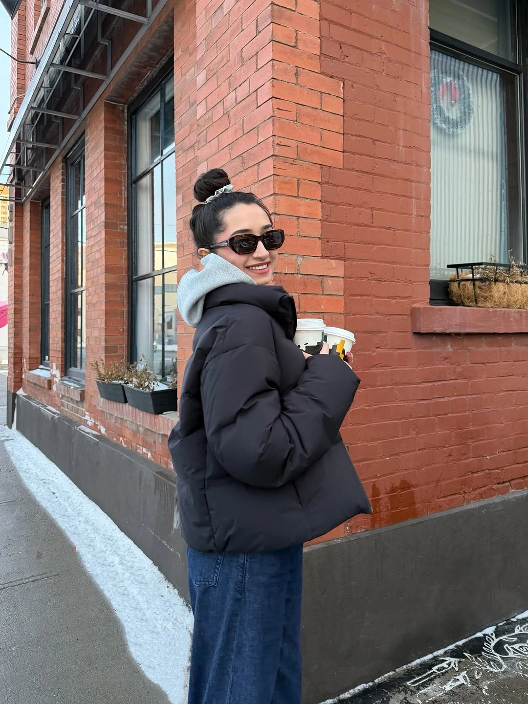 Black puffer-style jacket with pale blue hood and wide jeans