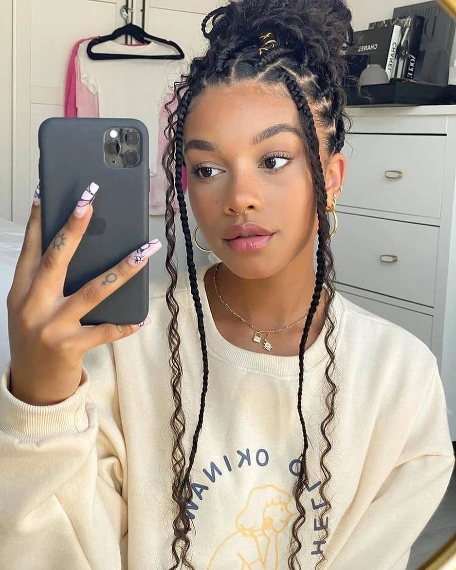 Dark cornrows pulled back into a low rounded bun or puff