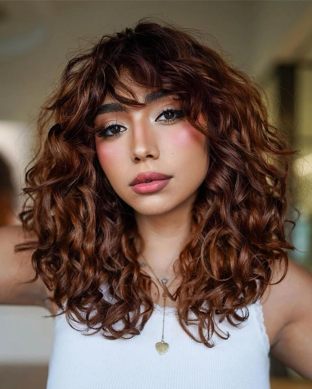 Shoulder-length curly auburn hair with curly bangs