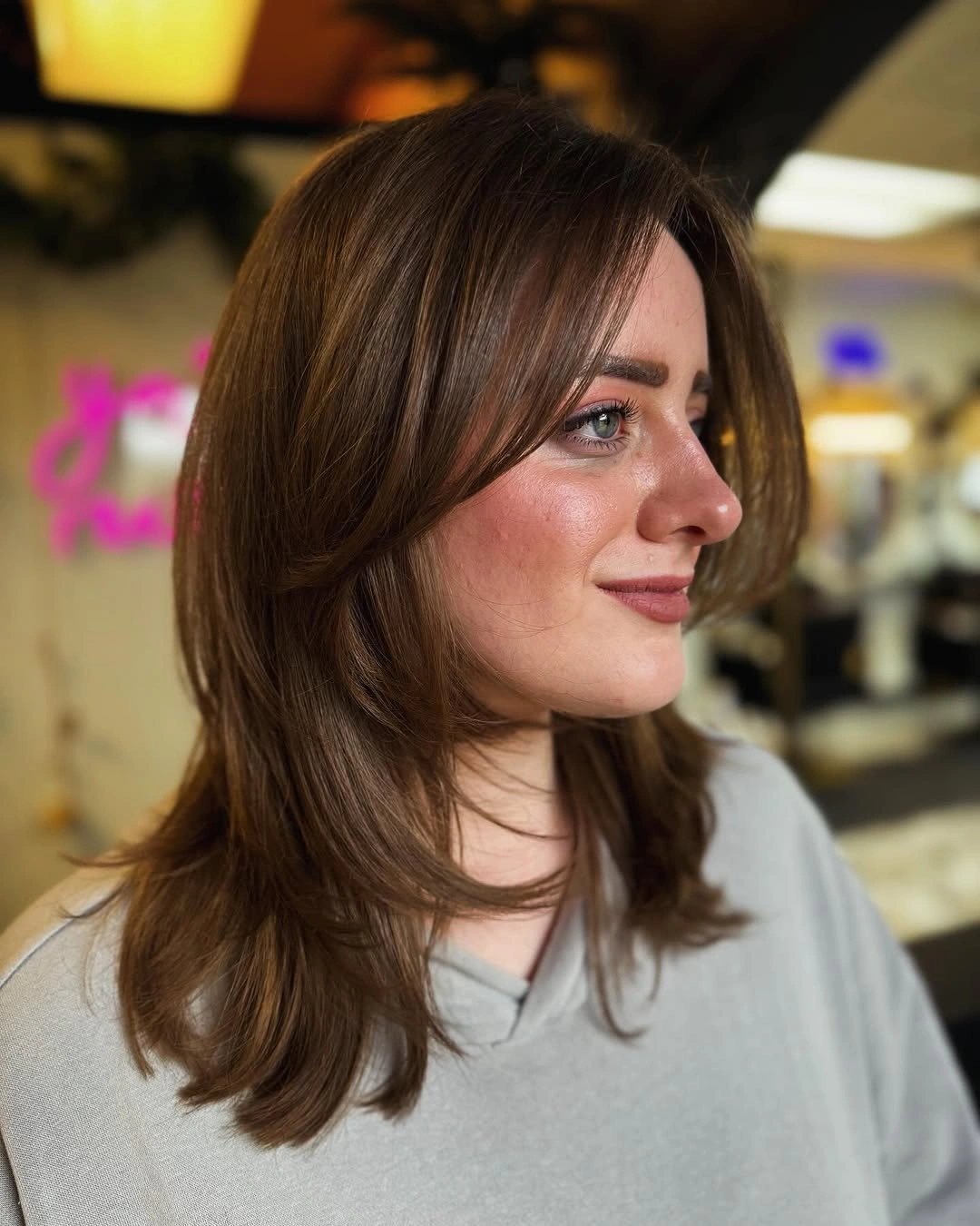Medium brunette layers with curtain bangs and warm shine