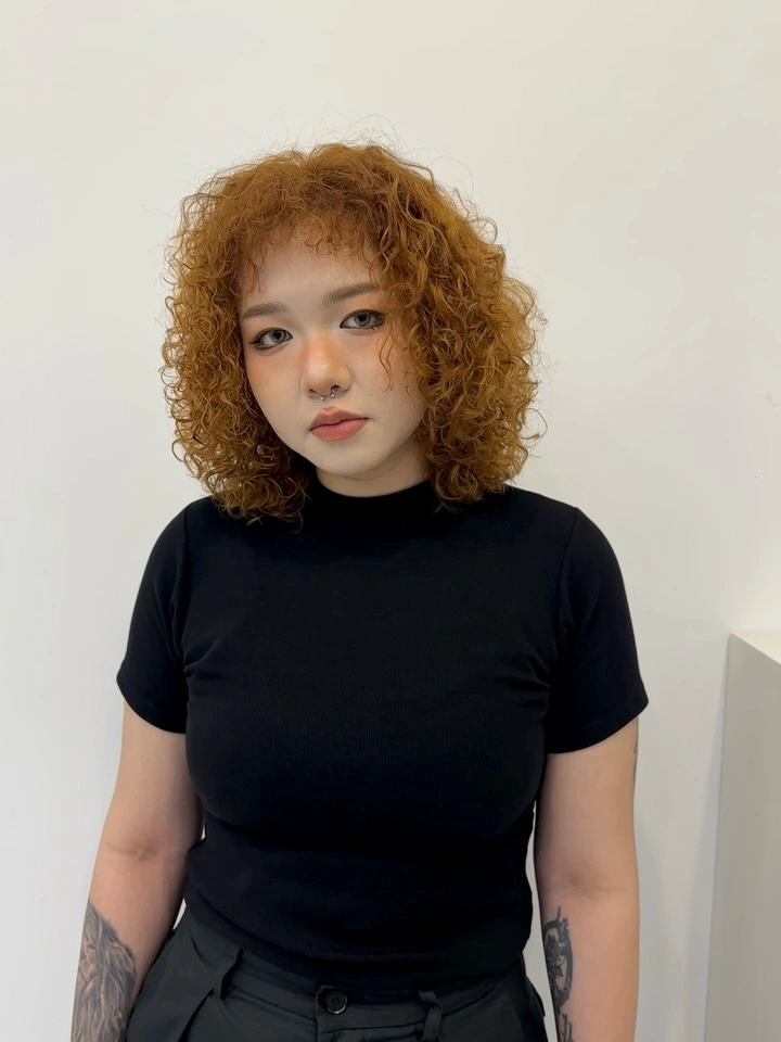 Curly bob with short curly bangs and rounded jaw-length shape