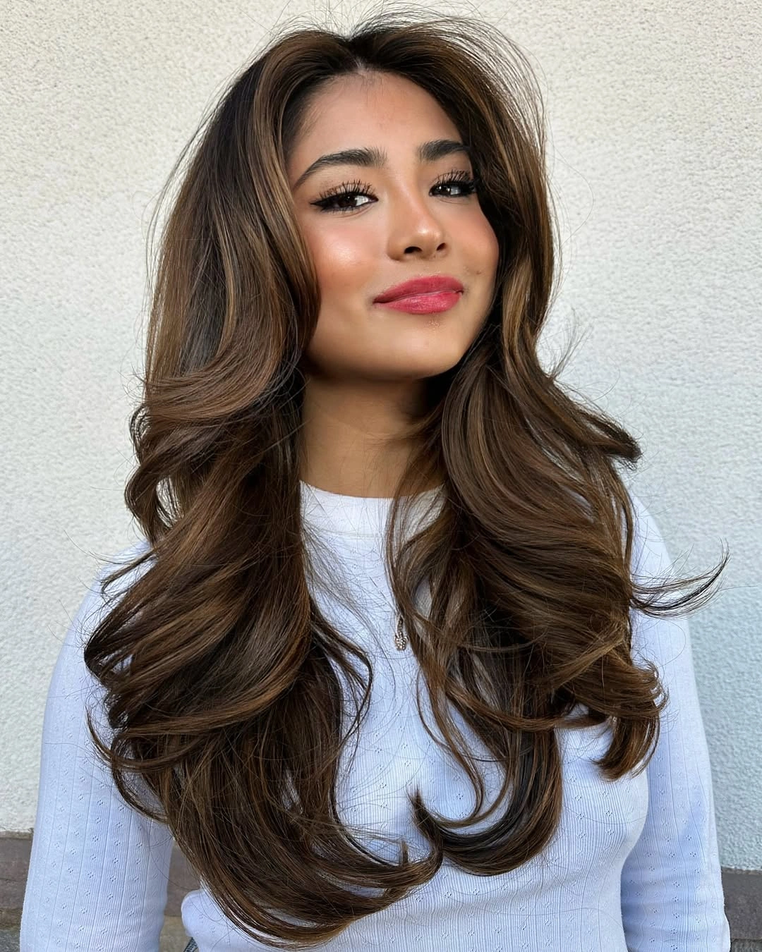 Long brown layered hair with face-framing pieces and curled ends