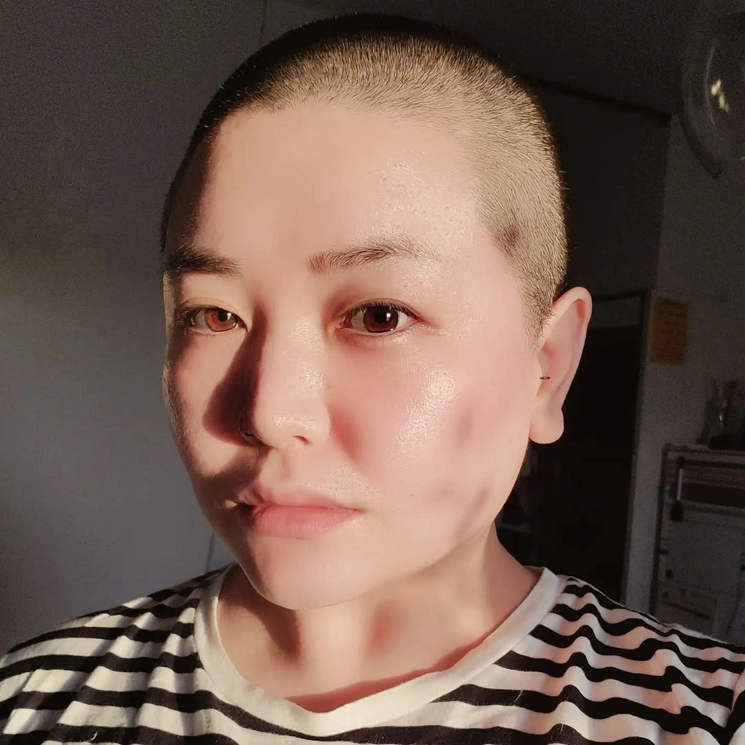 Very closely cropped dark hair following the head shape