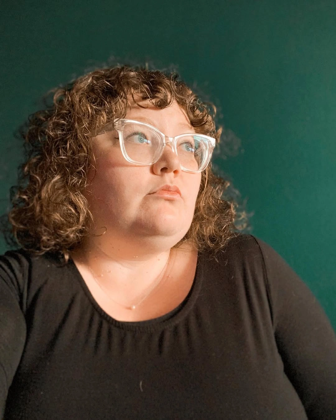 Curly brown bob with short fringe and light-colored glasses
