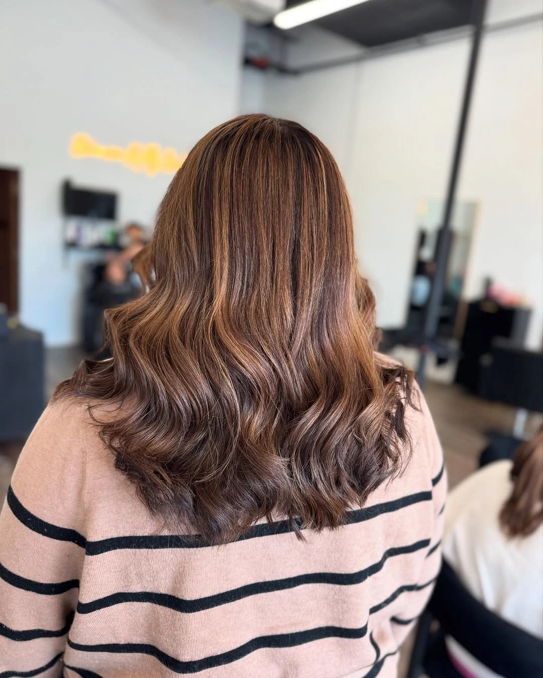 Long warm-brown layered hair with lighter ribbons and broad waves