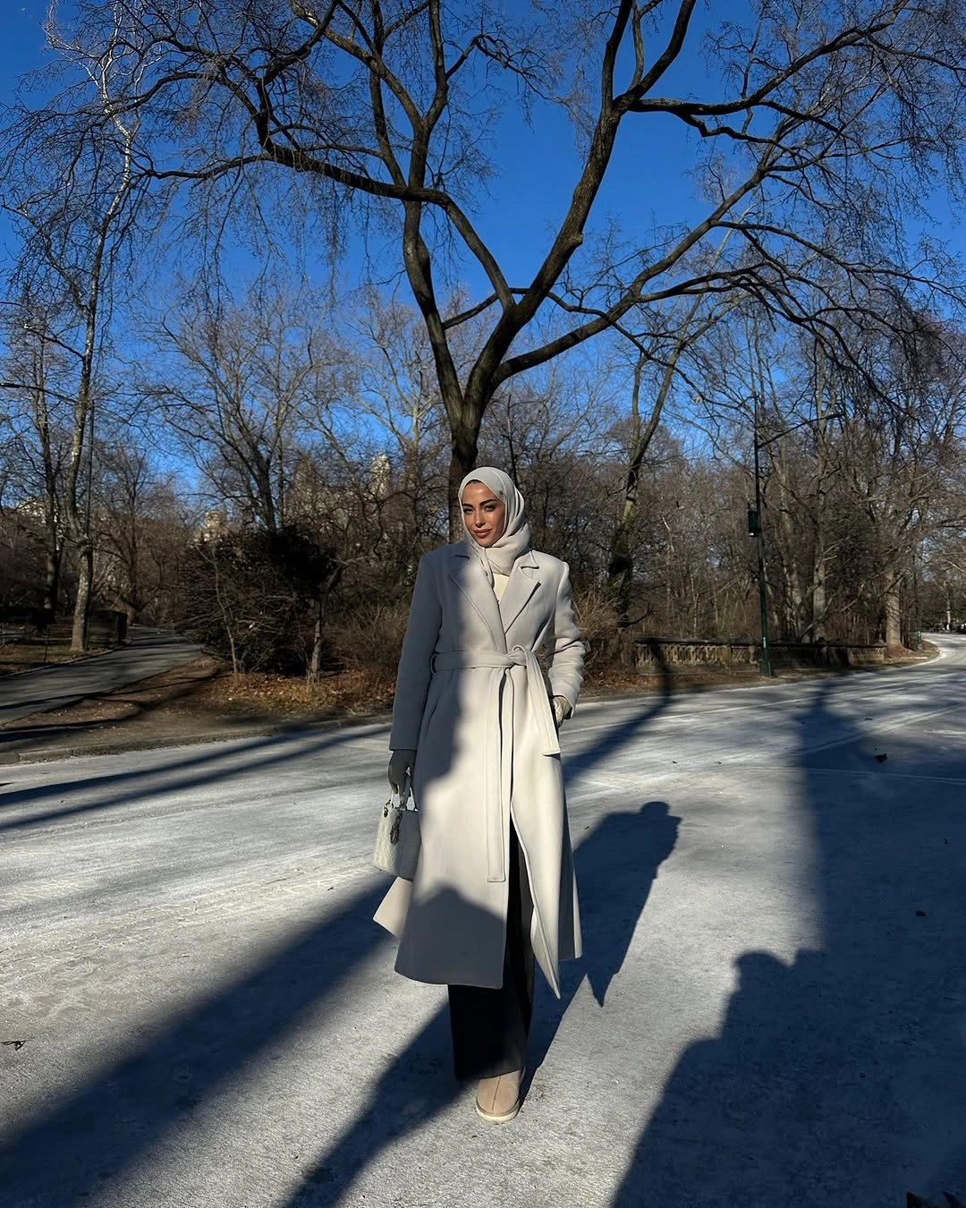 Light belted coat with black wide-leg trousers and pale bag