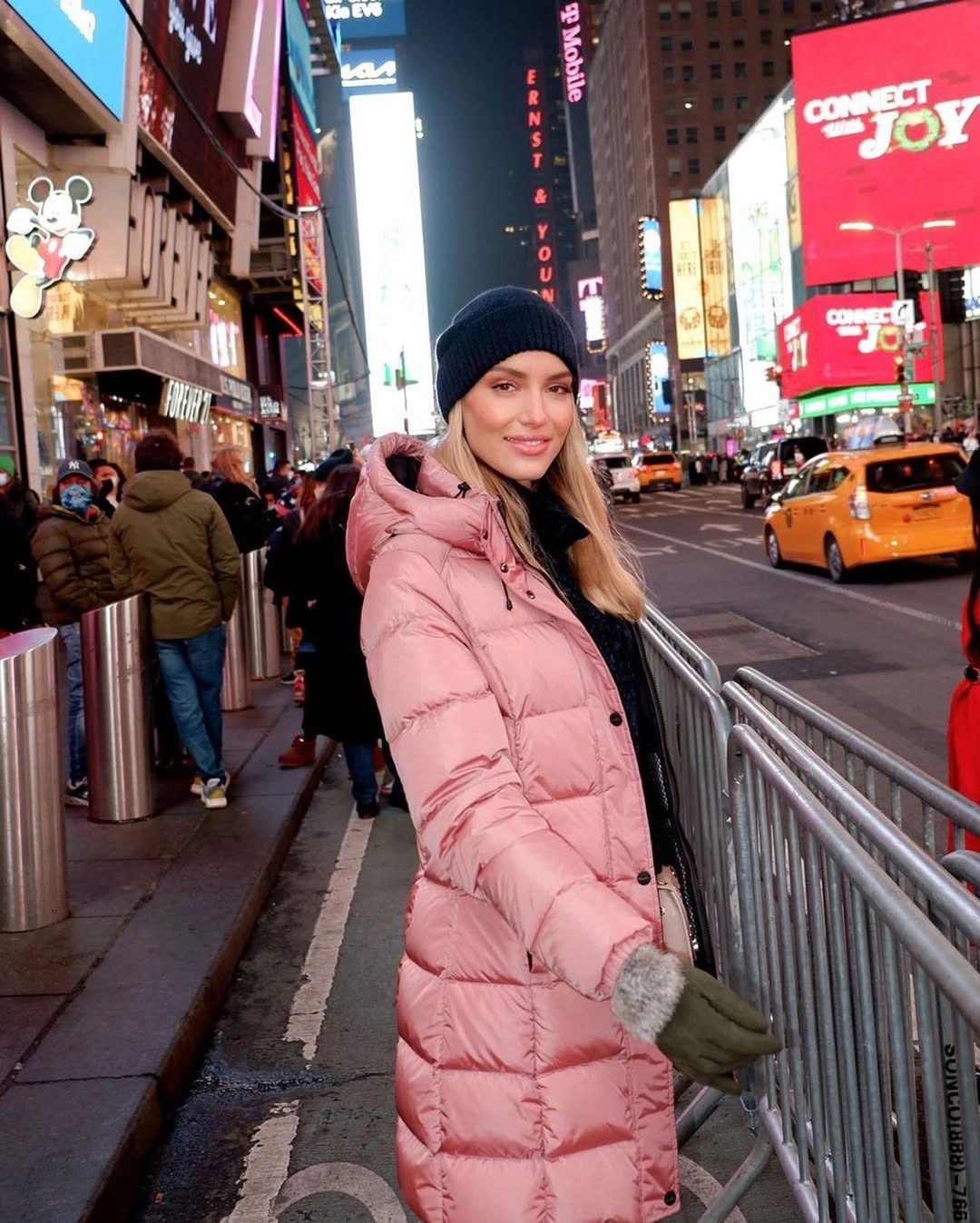 Long blush pink puffer with black beanie at night
