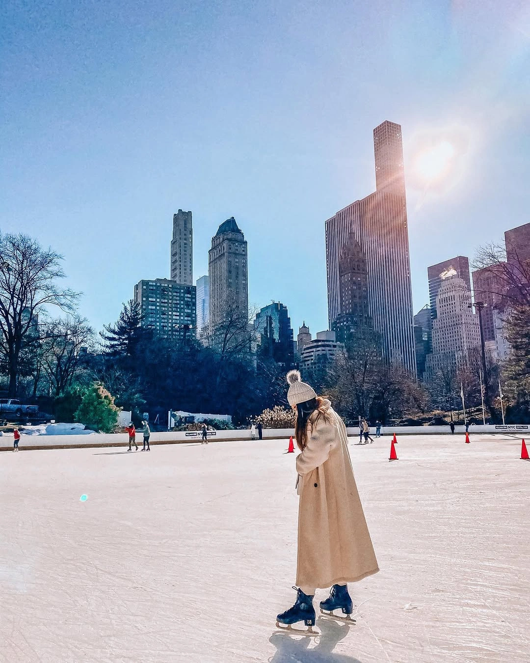 Long beige coat with blue ice skates on rink