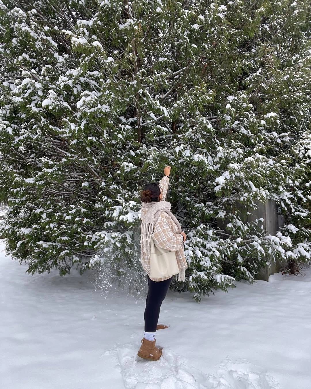 Cream fuzzy vest with plaid layer, dark pants, and tan boots