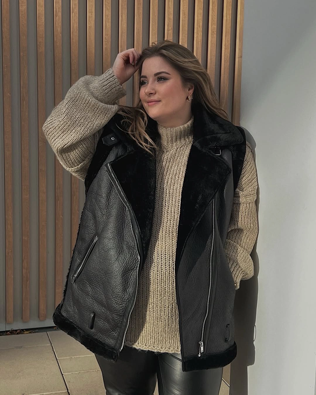Black fuzzy-trim vest over chunky beige turtleneck knit