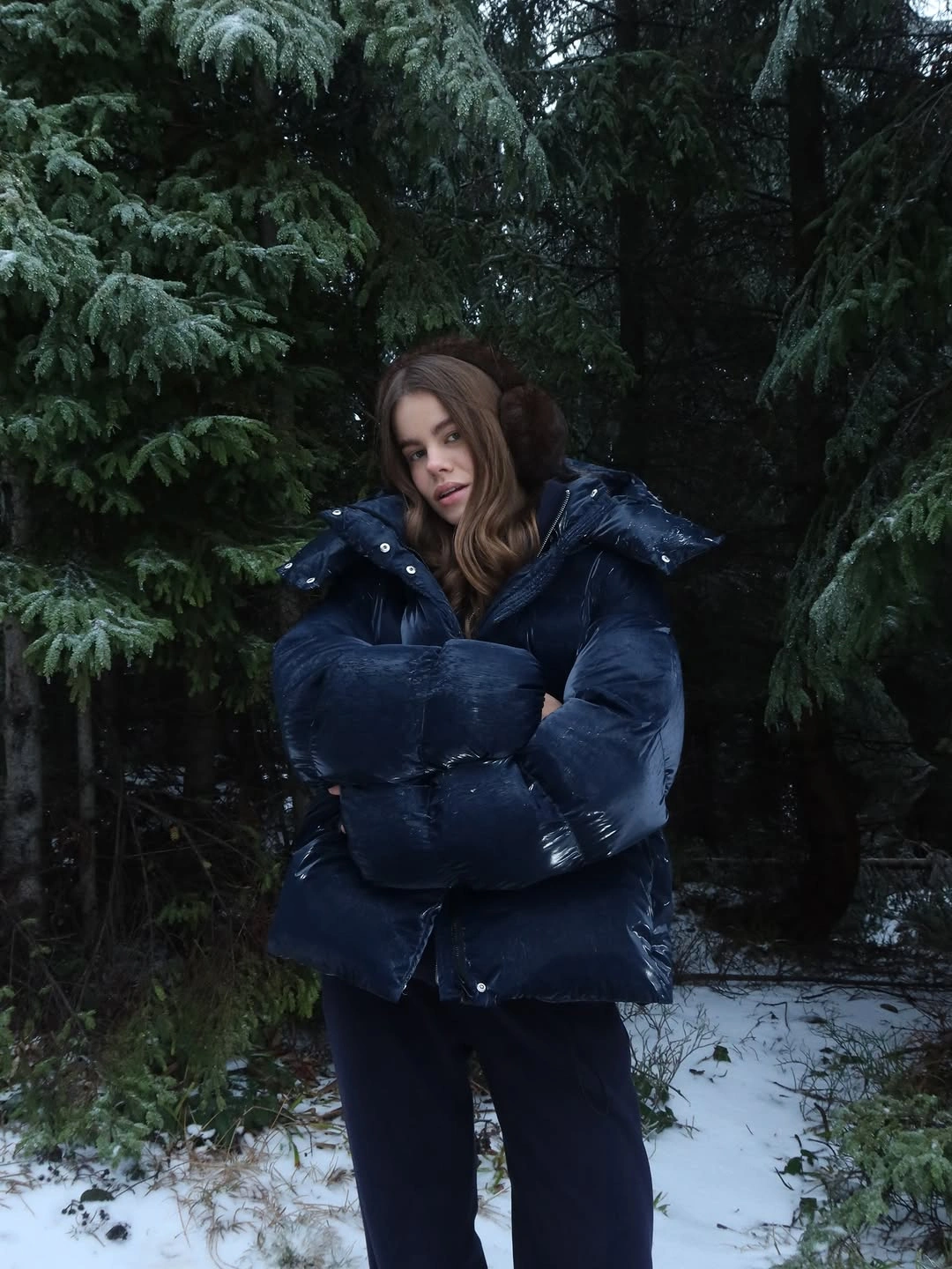 Glossy navy puffer with dark pants in snow