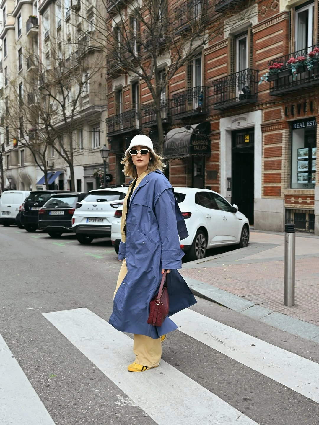 Dark gray belted coat with blue hoodie and pale pants
