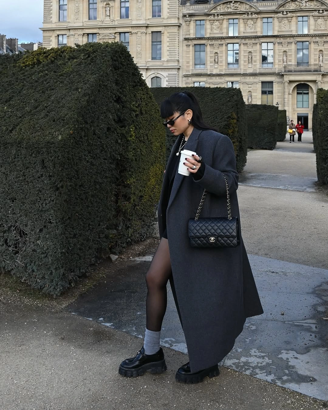 Long black coat with mini skirt, sheer tights, and chunky loafers