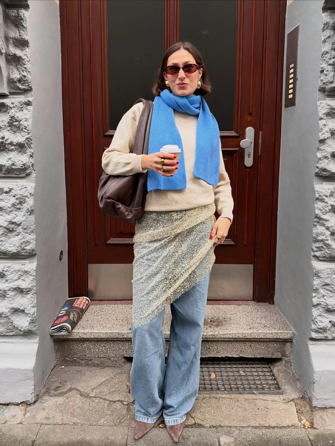 Cream knit with vivid blue scarf, pale jeans, and small bag
