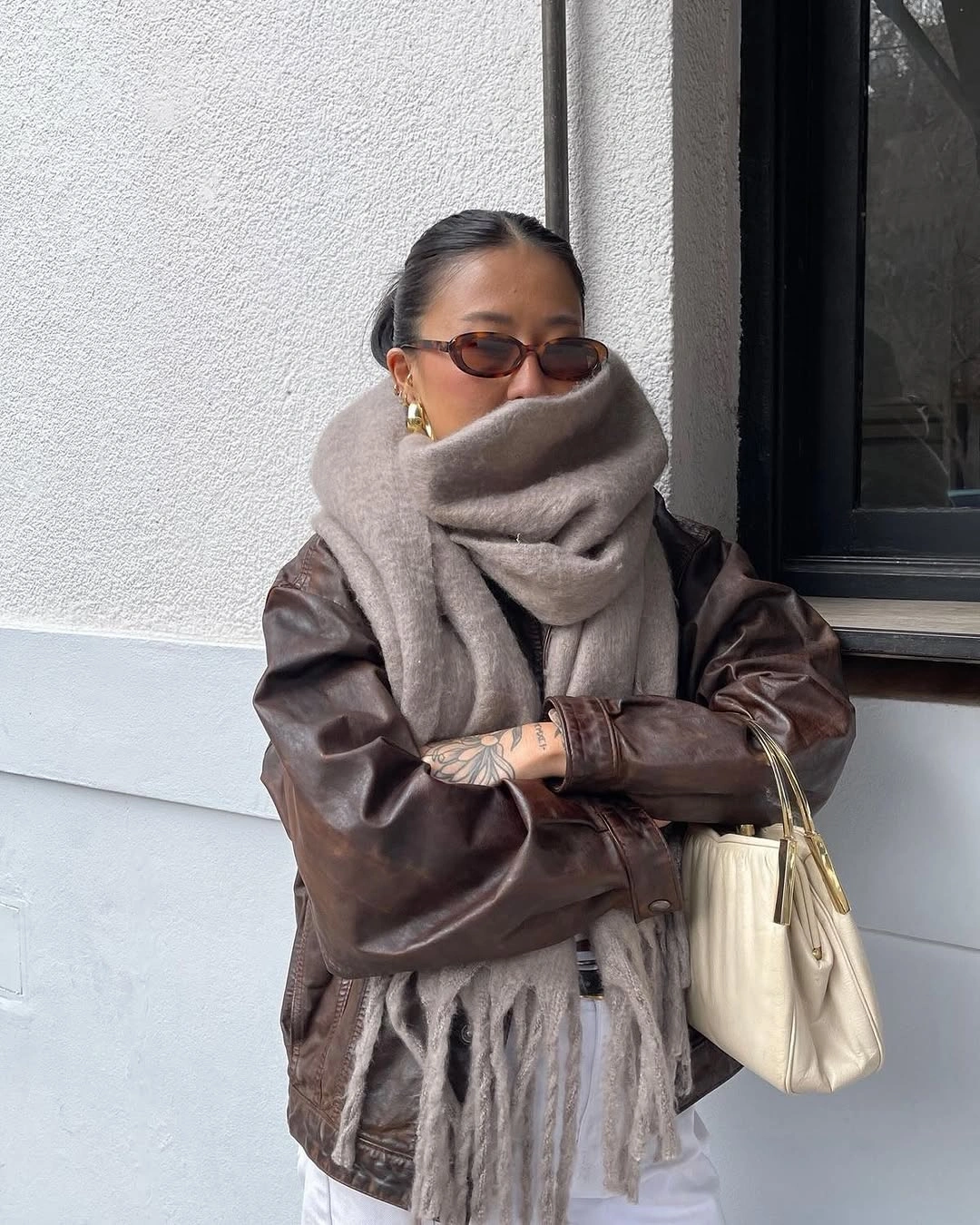Brown leather jacket with oversized taupe scarf and cream bag