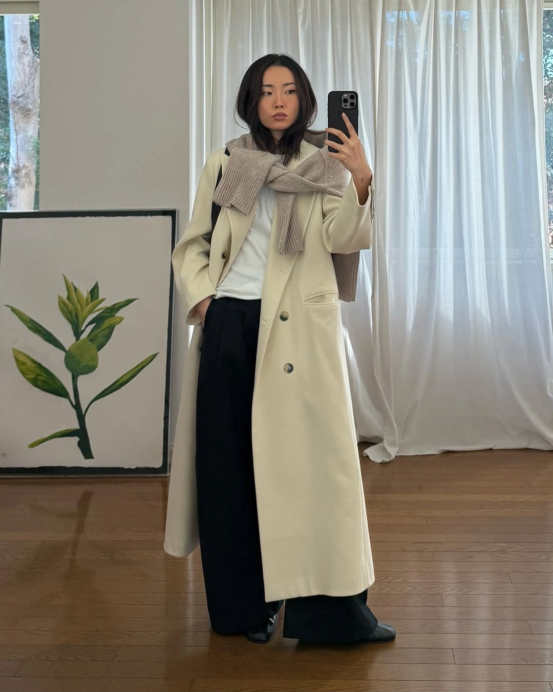 Cream double-breasted coat with black wide trousers and taupe scarf