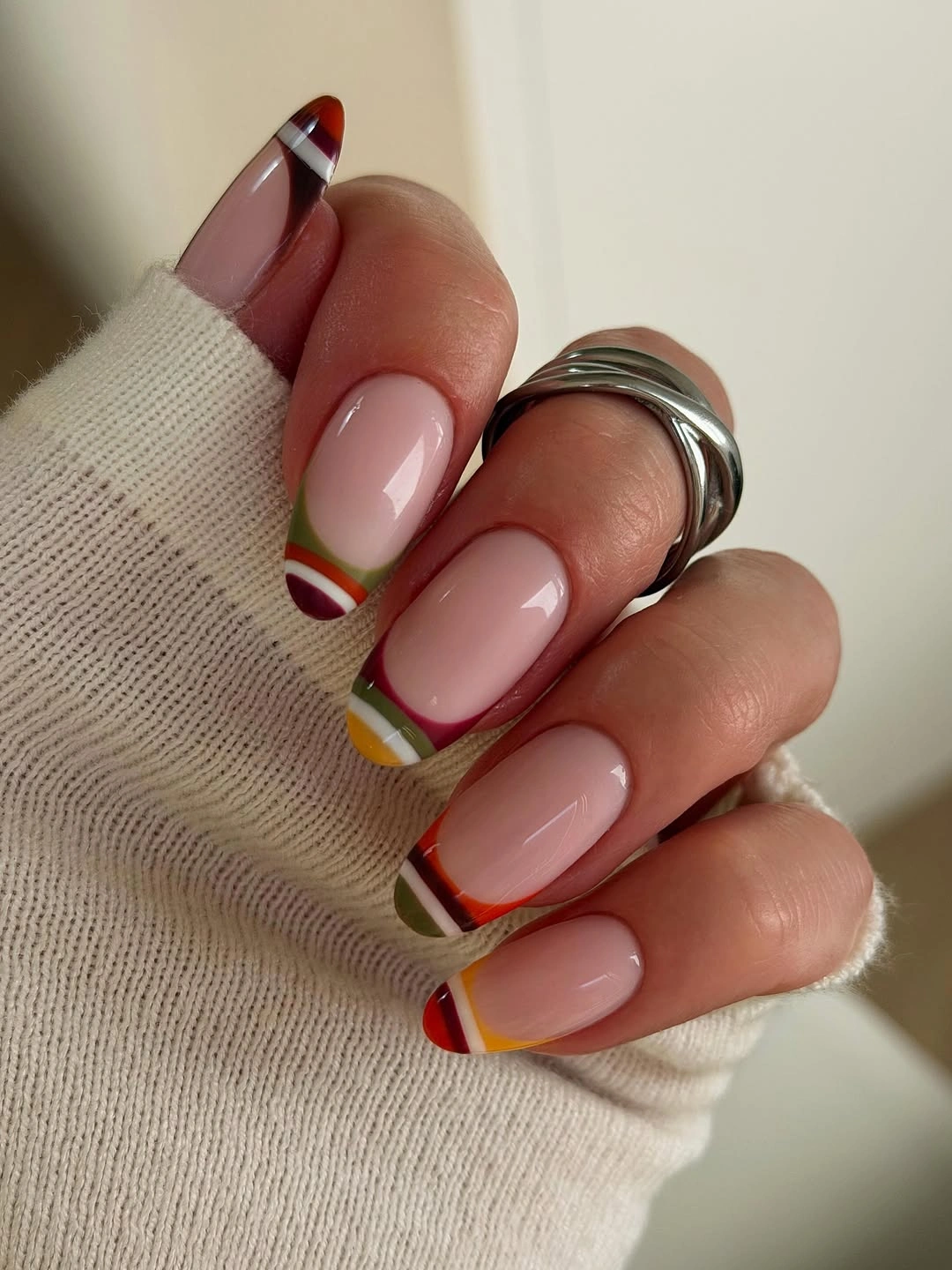 Almond nails with nude bases and curved multicolor tips