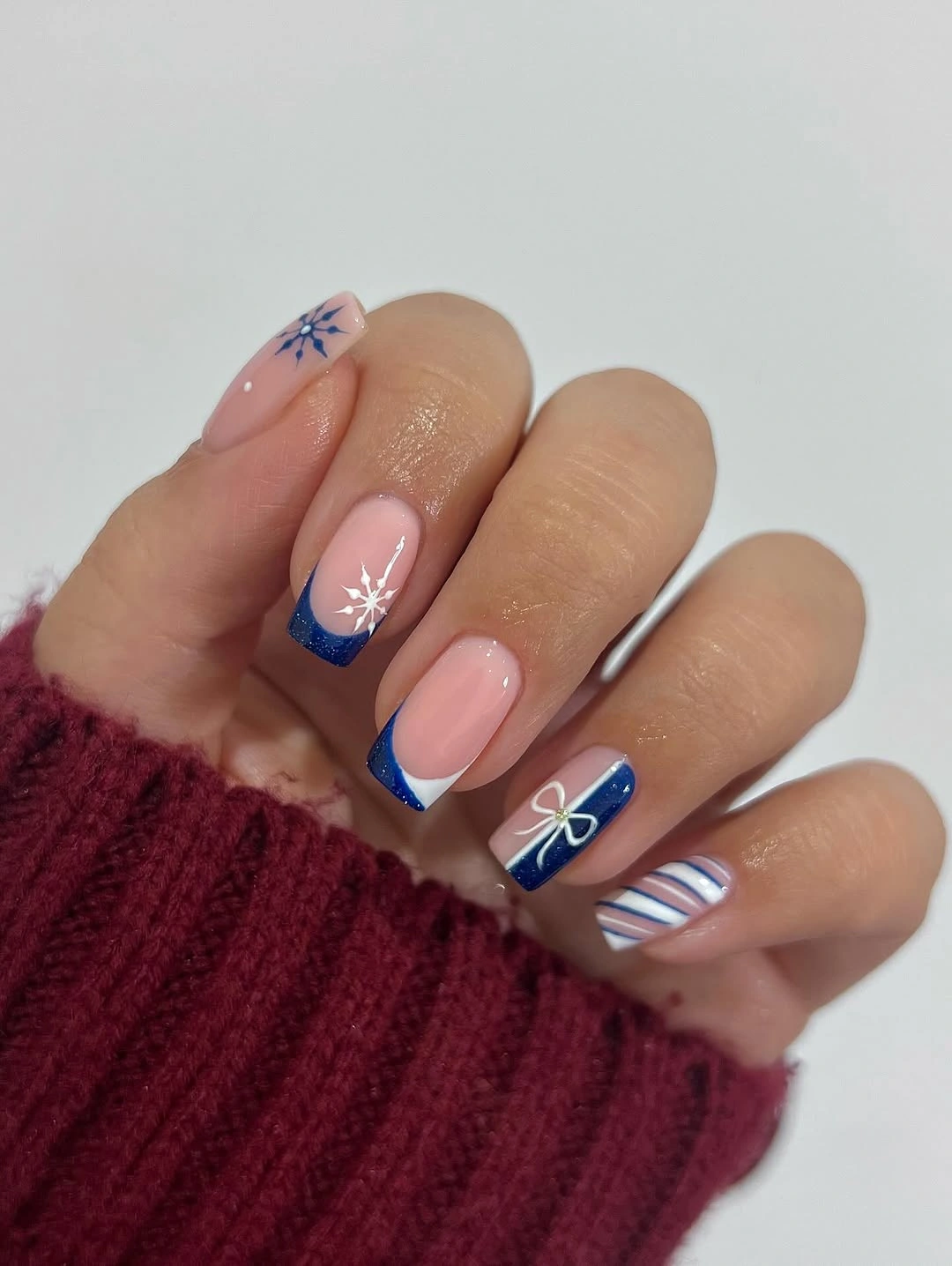 Square pink nails with blue tips, bow, stripes, and starbursts