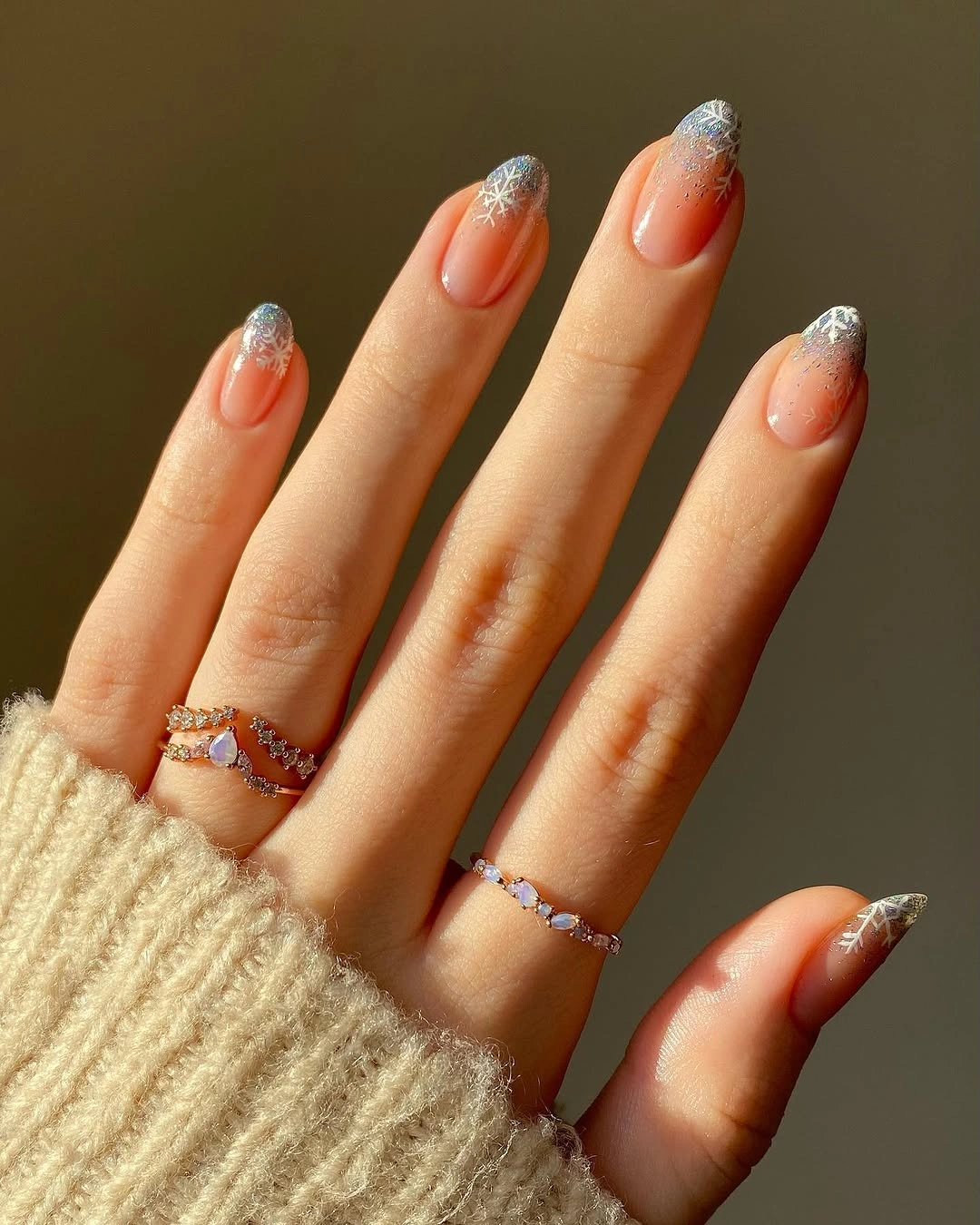 Long almond nude nails with silver glitter tips and snowflakes