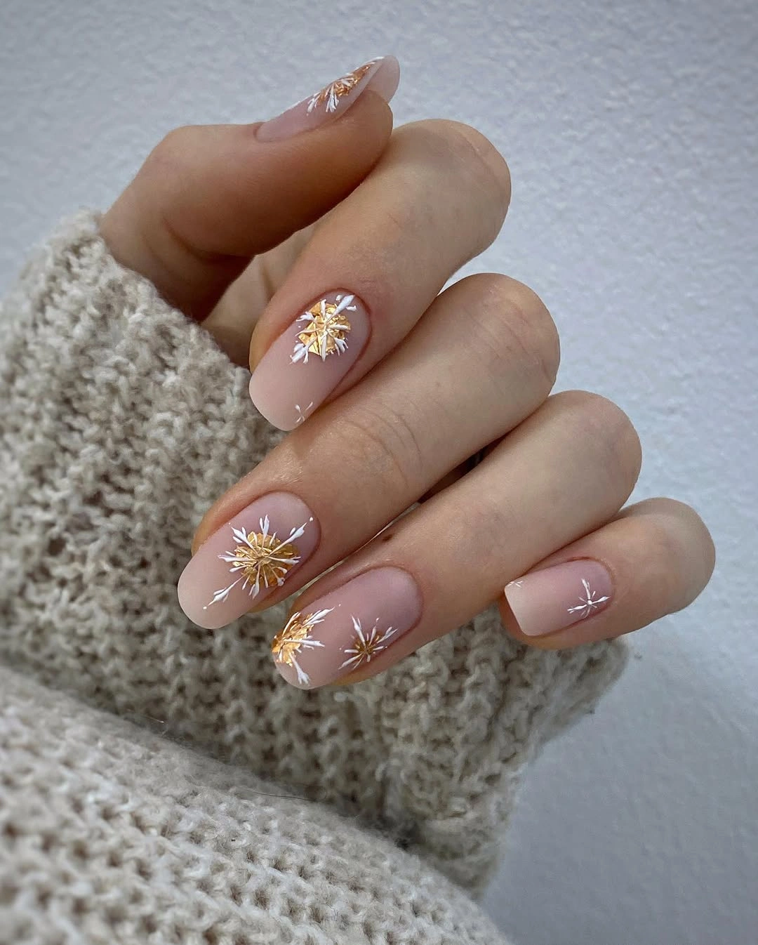 Short nude nails with white and gold starburst motifs