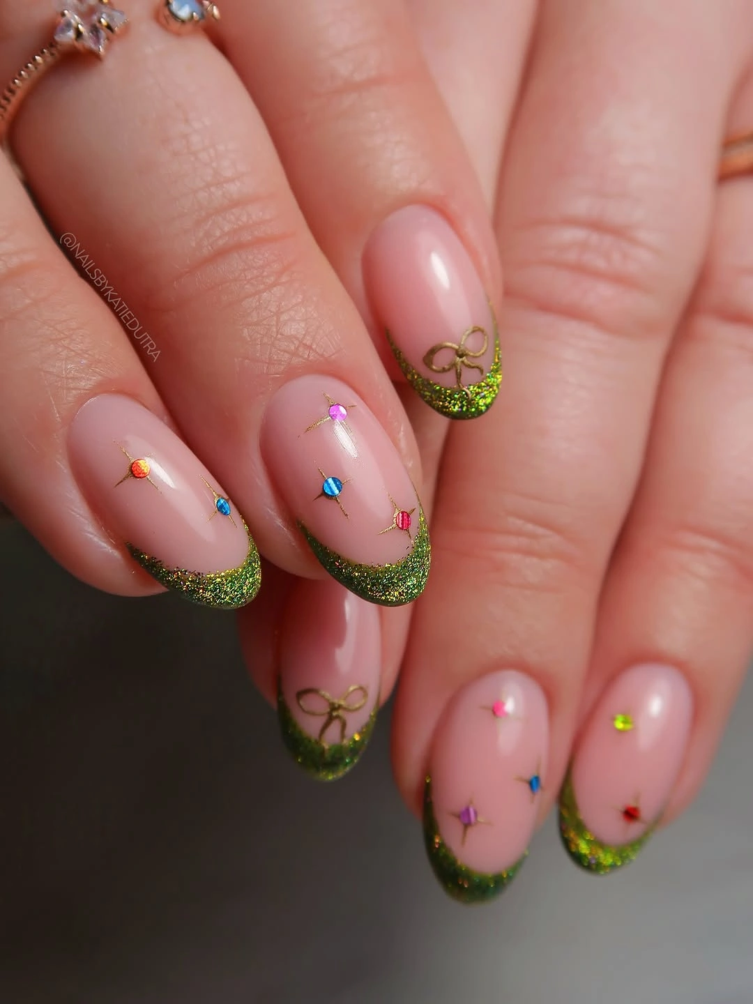 Short rounded nails with green glitter tips and colorful dots