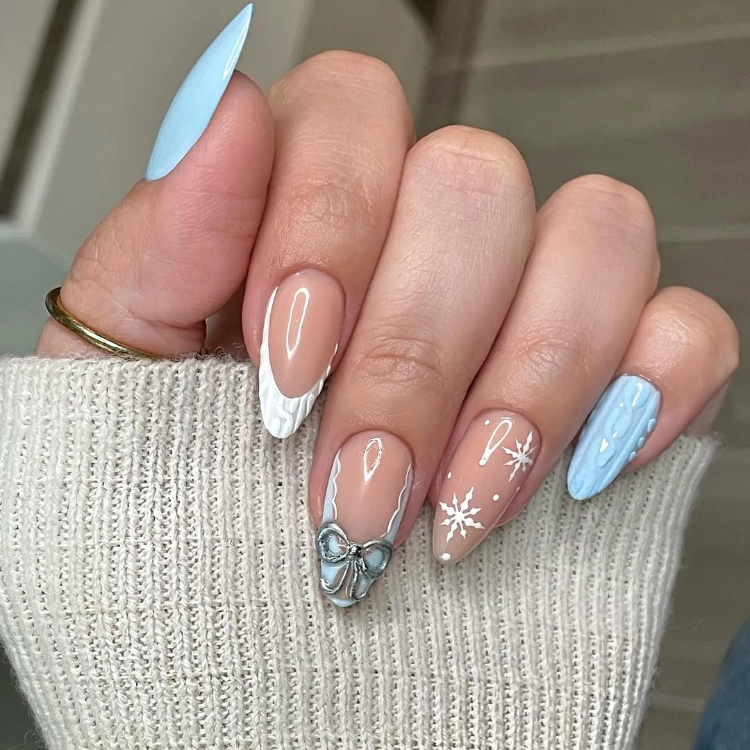 Long almond nails with blue texture, white bow, and snowflakes