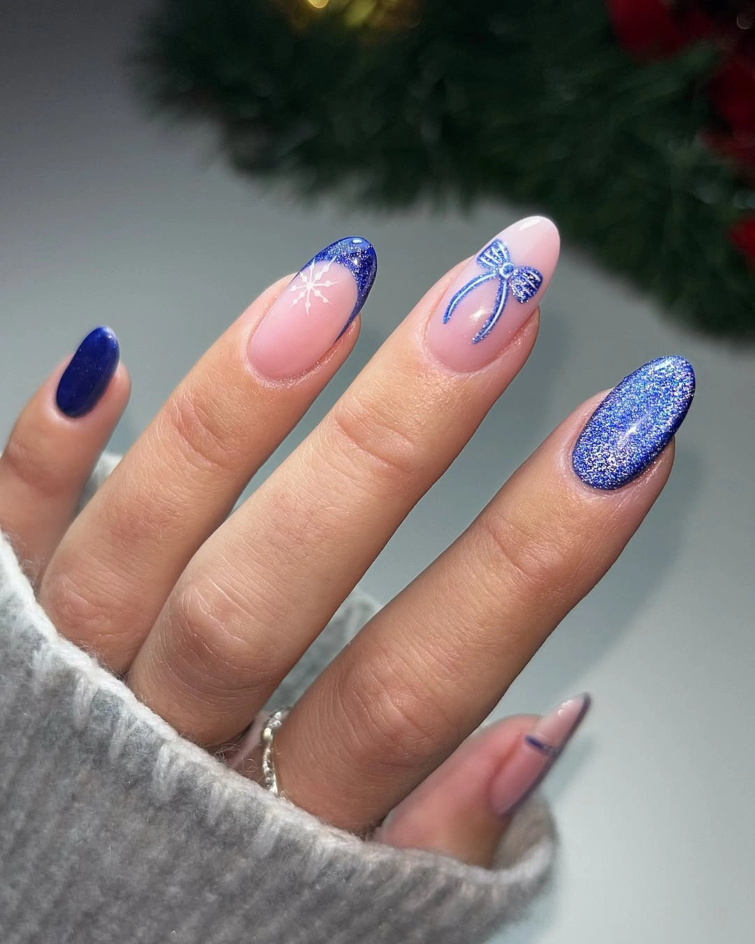 Almond nails with cobalt glitter, blue tips, and bow art