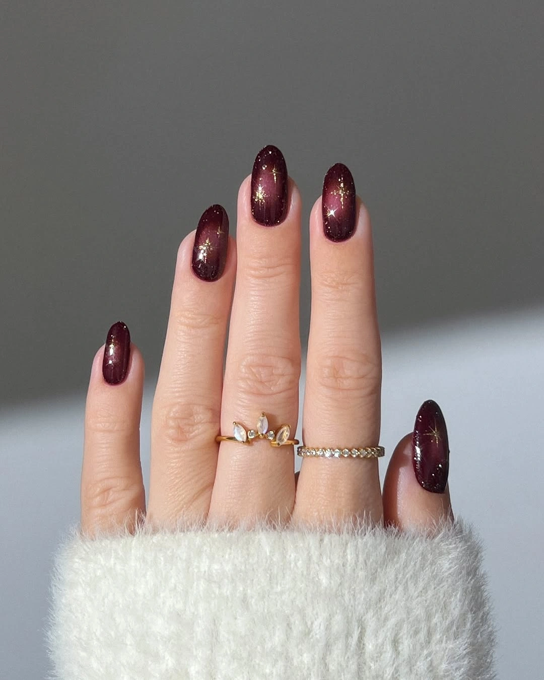 Rounded burgundy-plum nails with reflective shimmer bands