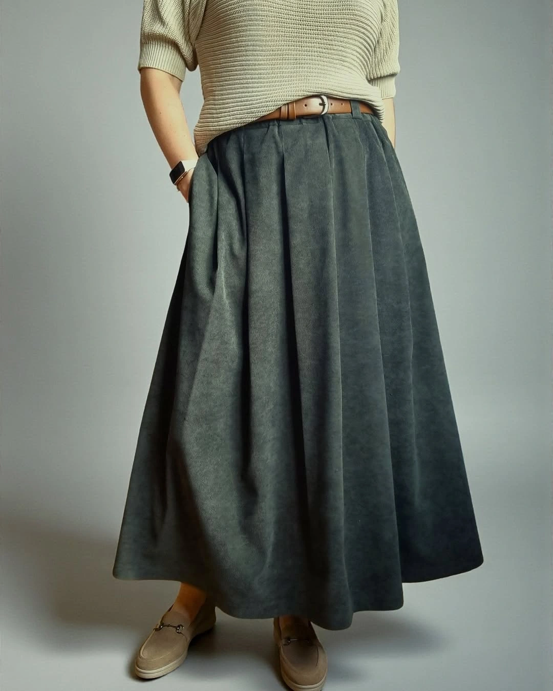 Pale knit top with charcoal full skirt and tan loafers