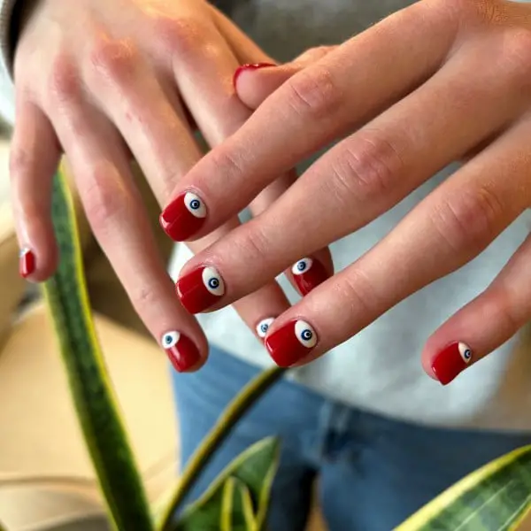Short Square Opaque Red Nails With Stylized Evil Eyes — Trendy Evil Eye Nails
