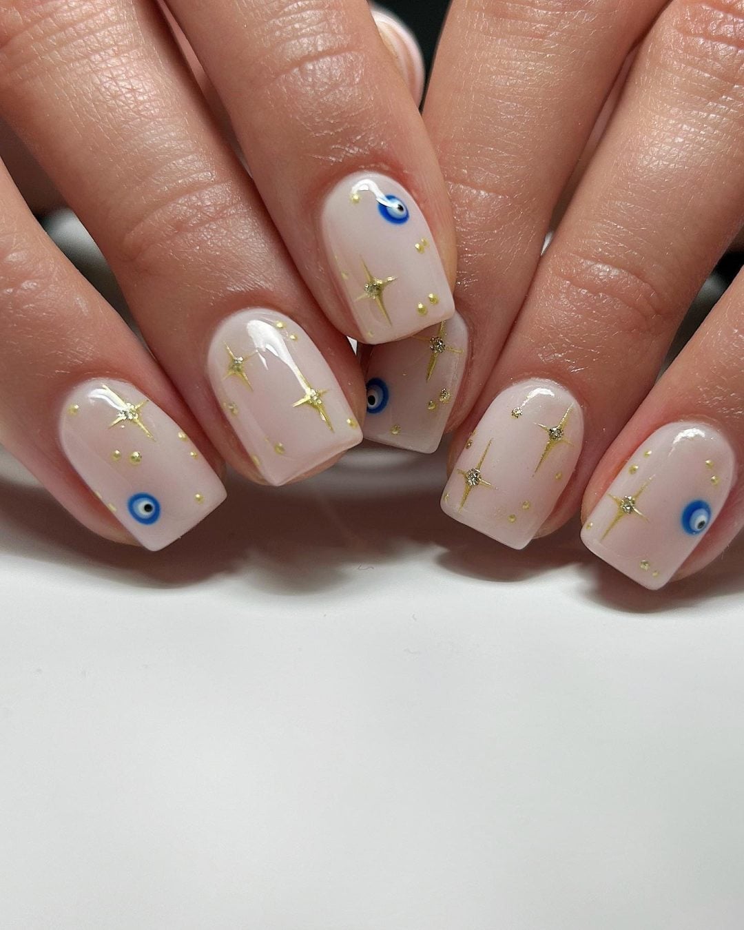 Medium Almond White Nails With Blue Eyes And Gold Stars — Trendy Evil Eye Nails