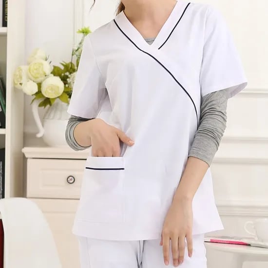 White Wrap V-neck Scrub Top Over Gray Shirt with White Pants, Fitted White Wrap V-neck Scrub Top Over Gray Shirt with White Pants, Fitted — Trendy Nurse Outfits